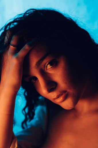 A portrait of a young sexy woman looking at the camera while fixing her hair on a blue background