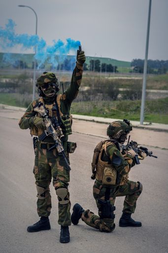 The special forces soldiers carrying out an operation using assault rifles and a blue smoke bomb