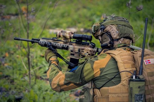 A side view of a special forces soldier aiming with an assault rifle