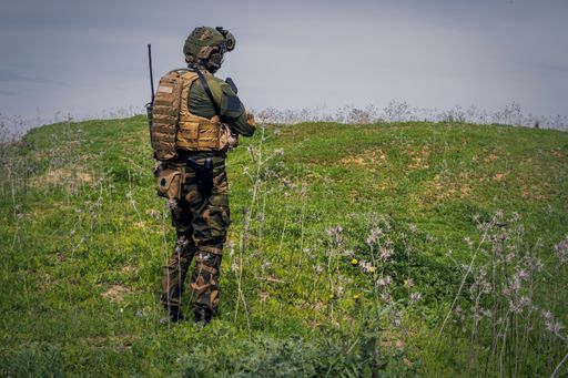 A back view of a fully equipped soldier on a military operation outdoors