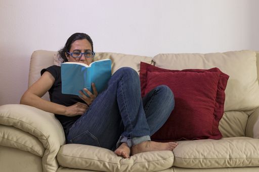 A caucasian girl enjoying a book on a sofa