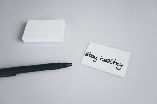 A closeup shot of a black pen and a pad of small paper with a stay healthy text on it