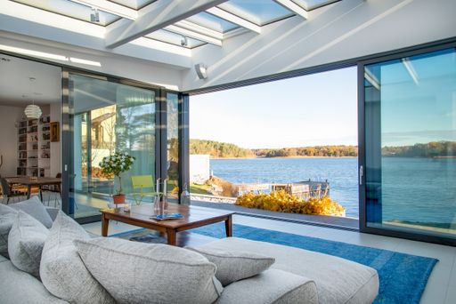 A luxury beach house with glass windows and the beautiful scenery of the sea in the background
