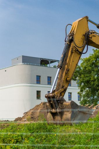 Yellow excavator in front of a new apartment building on a construction area