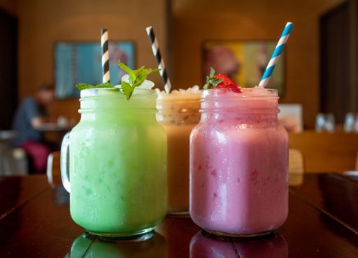 A closeup of three different flavored tasty Thai milk tea on a wooden table at a cafe with a blurred background