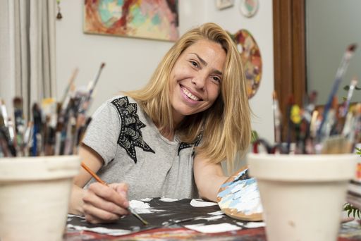 A closeup shot of a smiling female artist painting in the art studio - authentic concept