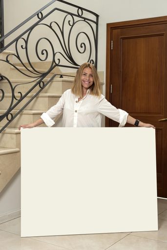 A vertical shot of a smiling female holding a blank canvas indoors - space for text