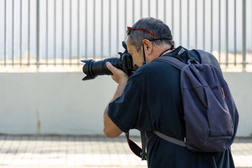 Stock photo of unrecognized man taking photos with his camera in the park.