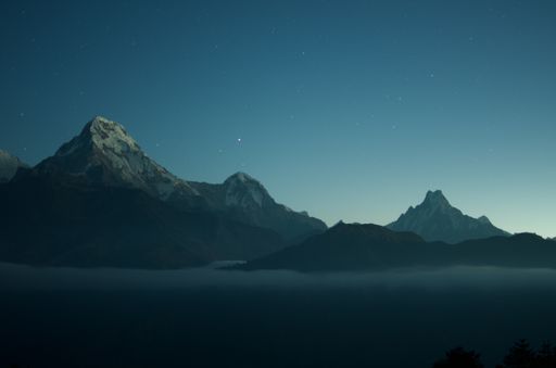 A wide shot of beautiful rocky mountains with amazing clear blue sky with stars in the background