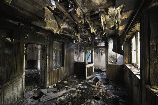 An inside shot of an abandoned destroyed building with burned walls and worn-out doors