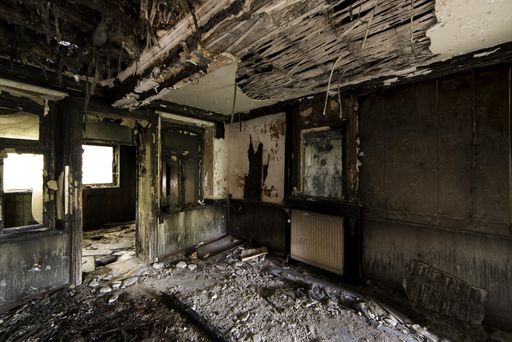 An inside shot of an abandoned destroyed building with burned walls and worn-out doors