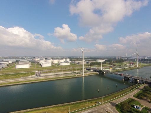 An aerial shot of the bridge going over the river leading to an industrial plant