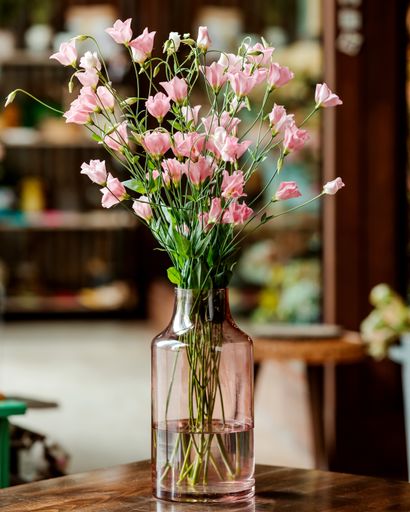 A vertical shot of blooming flowers in a glass vase indoors