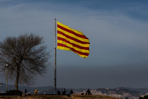Flag of Catalonia waving in the wind, at the castle on the mountain of Montjuic, with a cloud of pollution and Barcelona in the background
