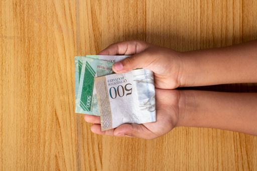 An overhead shot of a person holding cash money on a wooden background