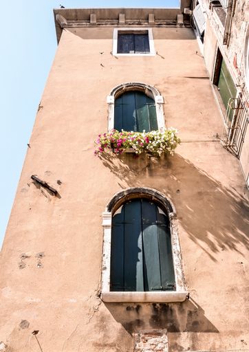 A low angle shot of three closed windows in a huge building