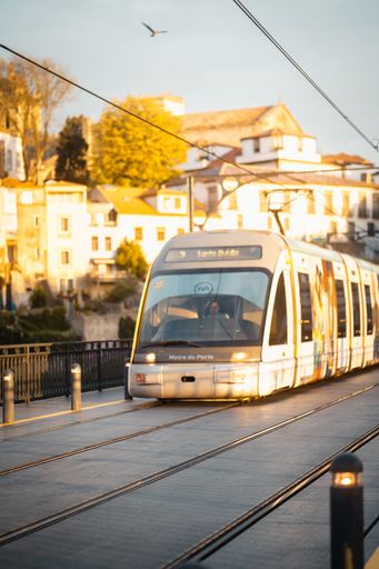 A vertical shot of an electric train on the background of dense buildings under a clear sky in Porto, Portugal