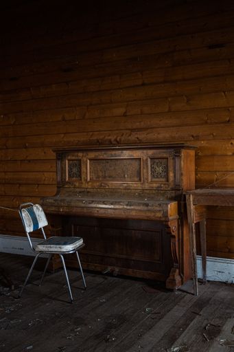 A vertical shot of an old piano and chair in an abandoned town hall, Australia
