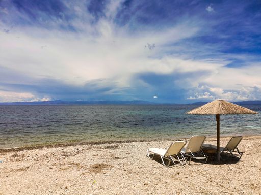 A beautiful view of the beach umbrella and chair sets on the sand near the beach on a sunny day