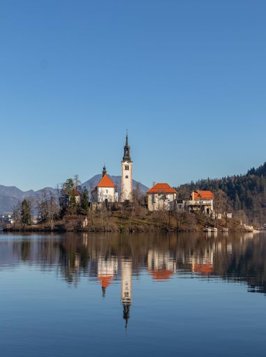 A the reflection of an old castle on the water surrounded by trees and mountains