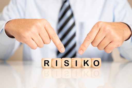 A male hand pointing to wooden cubes with the letters making the word risiko