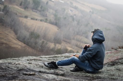 An unrecognizable man sitting on the edge of a cliff and admiring the unique landscapes and nature