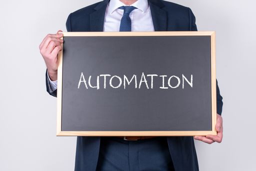 A businessman wearing a suit and holding a blackboard with the word AUTOMATION written on it