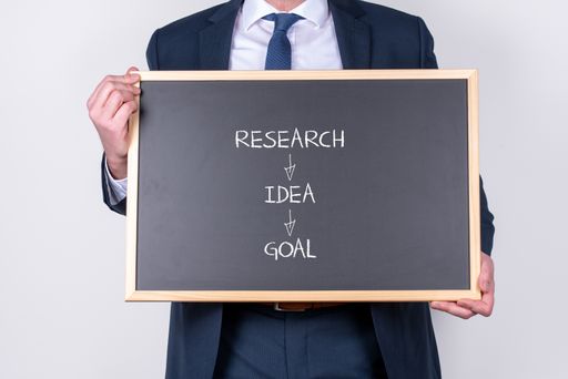 A businessman wearing a suit and holding a blackboard with a working strategy written on it