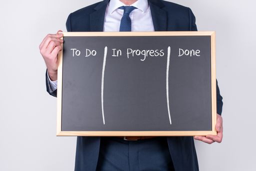 A businessman wearing a suit and holding a blackboard with the planning of working written on it