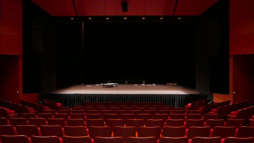 Empty stage with a few props and red audience seats
