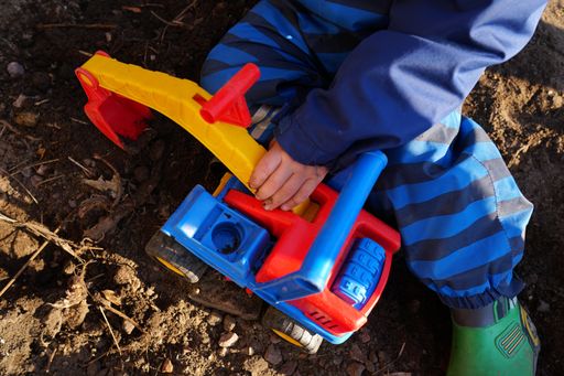 A kid playing with a car toy in a park