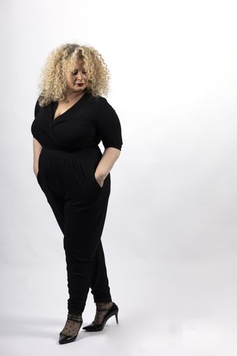 A vertical shot of a mature plus-size female model wearing black clothes on a white background