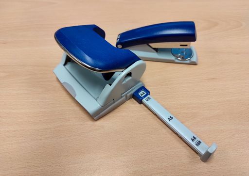 A closeup shot of a blue tacker and hole punch on a wooden table