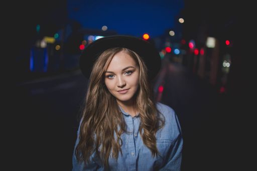 A beautiful Bosnian Caucasian woman in a hat posing in the street during night time