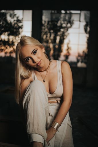 A vertical shot of a sexy Bosnian blonde woman wearing a crop top posing in an abandoned building