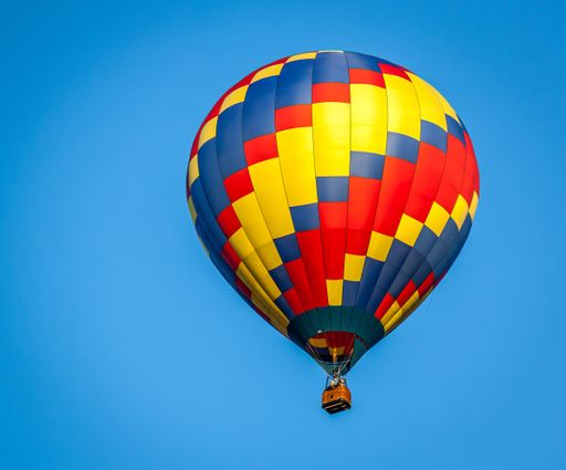 A closeup of a colorful hot air balloon against a clear blue sky