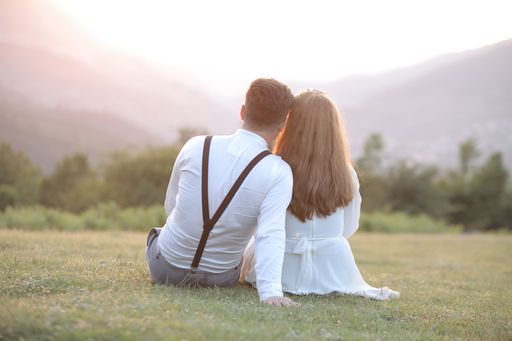 An affectionate couple enjoying a beautiful outdoor view, sitting on a lush green grassy hill