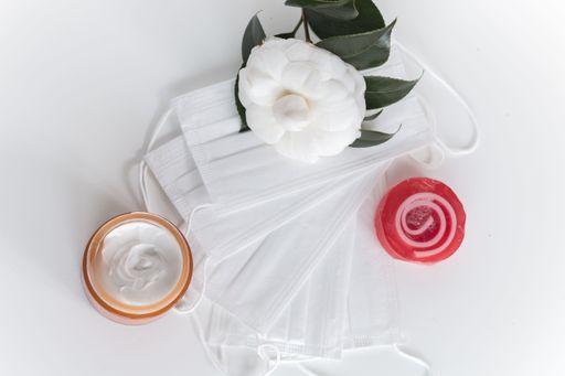 A face cream with face masks and flowers on white background