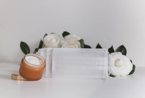 A face cream with face masks and flowers on white background
