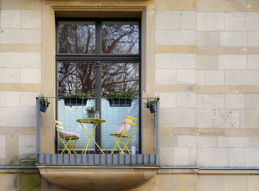 the tiny balcony with two yellow chairs and a table of a residential house in Cologne, Germany