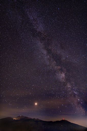 A vertical picture of rocks under a starry sky during the night