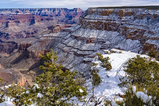 The view shows a beautiful sunny day at the Grand canyon after a snowfall has coated the rocks