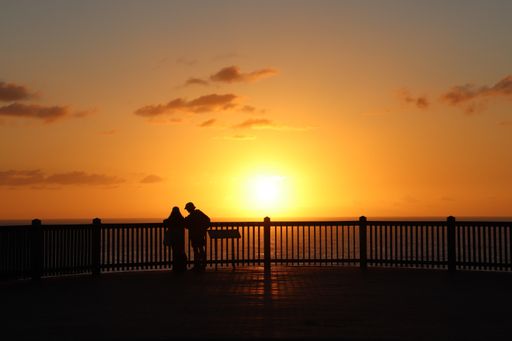 The silhouette of a couple leaning on the rails near the sea in Kiama, South Coast, Australia at sunset
