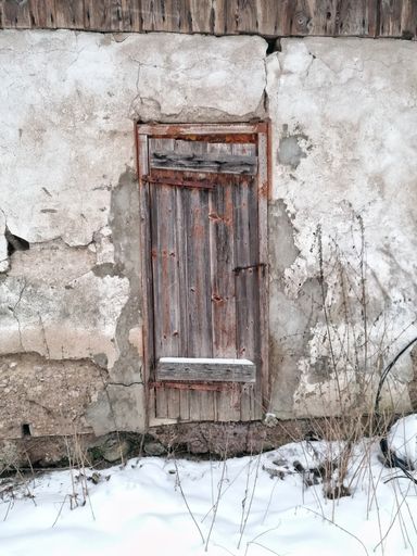 A vertical shot of an old rural wooden door of an ancient rural house