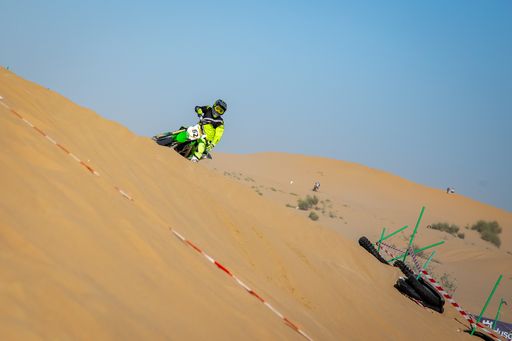 Motocross riders on racecourse in the desert with protective gear sand and clear skies