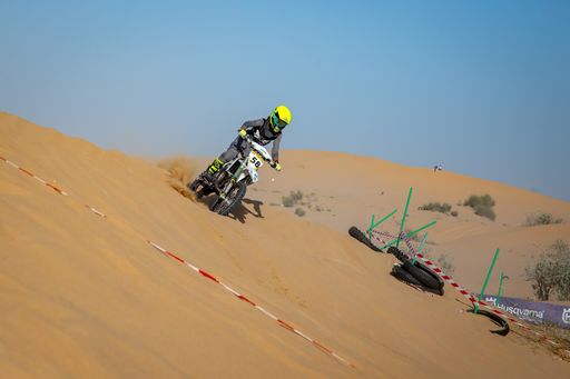 Motocross riders on racecourse in the desert with protective gear sand and clear skies