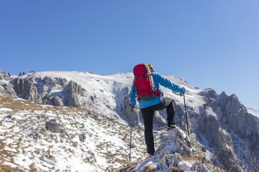 A back view of a hiker looking at the view from a snowy mountain peak