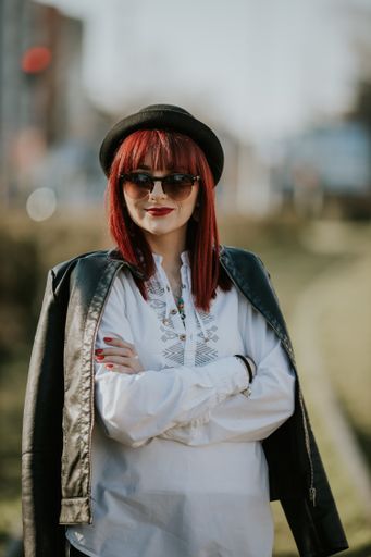 A vertical shot of a beautiful caucasian woman with red hair posing in a park during daylight