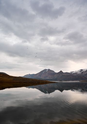 A beautiful scenic view of the Azat reservoir in Armenia with the reflection of mountains on a cloudy day