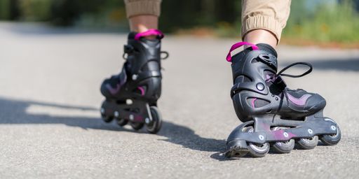 A panoramic shot of black roller skates on a gray asphalt